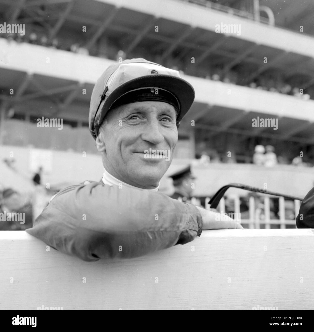 Epsom, Surrey, Inghilterra: Un sorriso così vincente sul volto del jockey australiano Scobie Breasley che è raffigurato appoggiarsi su una recinzione qui oggi. Breasley in su sul monte irlandese addestrato Babbo Natale, ha vinto il £72,067 185th Derby Stakes Babbo Natale è di proprietà di John Ismill. In secondo luogo è stato l'Indiana, guidato da J. Lindley e di proprietà di New Yorker, Charles W. Engelhard e terzo è stato dilettante, guidato da P. Matthew e di proprietà di New York Cosmetics Tycoon Larry Gelb. 3 giugno 1964 Foto Stock