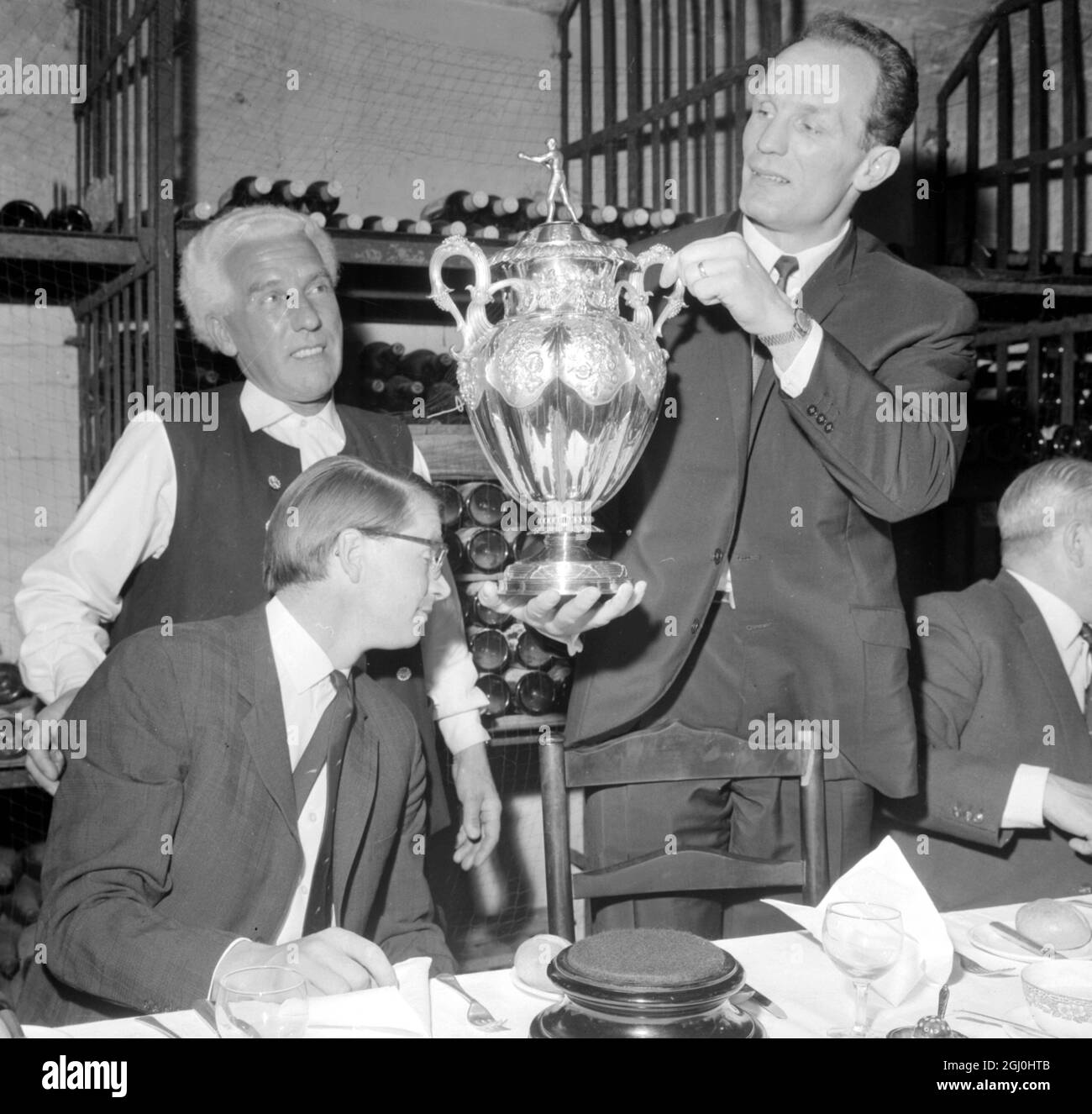 Londra: Oggi mostra British Heavyweight Champion Henry Cooper tenendo la boxing News God Cup ad un pranzo di scrittori sportivi nel Cheshire Cheese, Fleet Street, Londra. A sinistra in primo piano è John Brumley, presidente dell'associazione di scrittori sportivi, E dietro di lui c'è Andrew Wilson Reed, House Historian del Cheshire Cheese. 3 maggio 1966 Foto Stock Londra: Oggi mostra British Heavyweight Champion Henry Cooper tenendo la boxing News God Cup ad un pranzo di scrittori sportivi nel Cheshire Cheese, Fleet Street, Londra. A sinistra in primo piano è John Brumley, presidente dell'associazione di scrittori sportivi, E dietro di lui c'è Andrew Wilson Reed, House Historian del Cheshire Cheese. 3 maggio 1966 Foto Stock