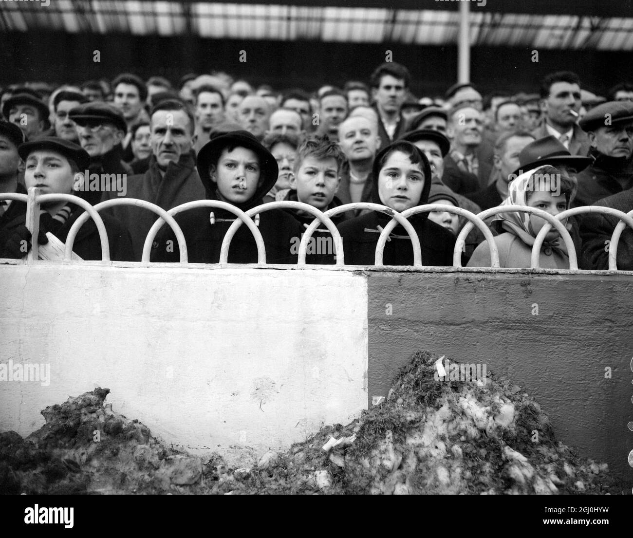 Londra: Con i tumuli di neve spazzati via dal campo di gioco in primo piano, questi spettatori giovani e anziani hanno sfidato il freddo per guardare la loro squadra preferita a White Hart Lane. 16 gennaio 1960 Foto Stock