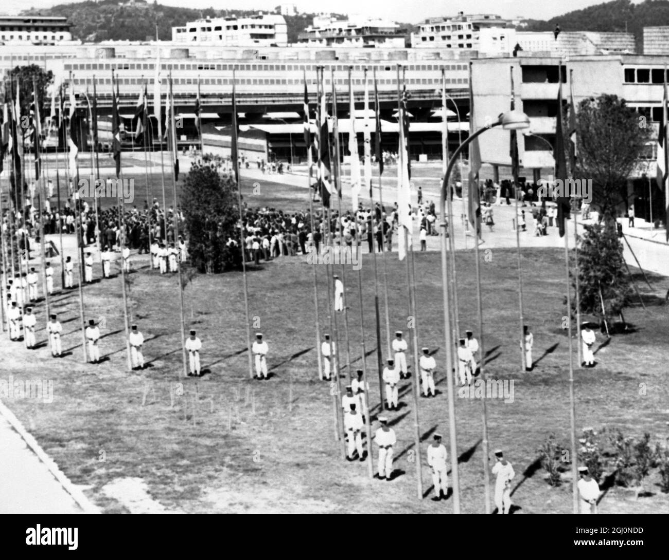 Roma : i marinai italiani stanno in guardia mentre il ' Villaggio Olimpico' entra in essere qui, pronto per i Giochi Olimpici del mese prossimo . Ogni palo di bandiera ha la bandiera di una nazione che vola da esso. 25 luglio 1960 Foto Stock