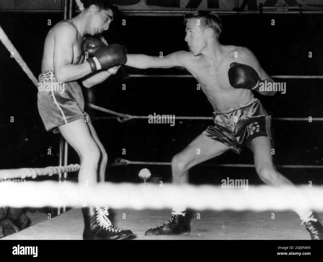 Jimmy Carruthers of Australia bussa a Vic Toween per una battuta d'arresto nel primo round del loro campionato mondiale di peso di bantam lotta qui a Johannesburg , Sudafrica . Prima del knock-out , poco dopo due minuti di combattimento , i Carruthers bussarono il sudafricano fuori dal ring due volte. 18 novembre 1952 Foto Stock