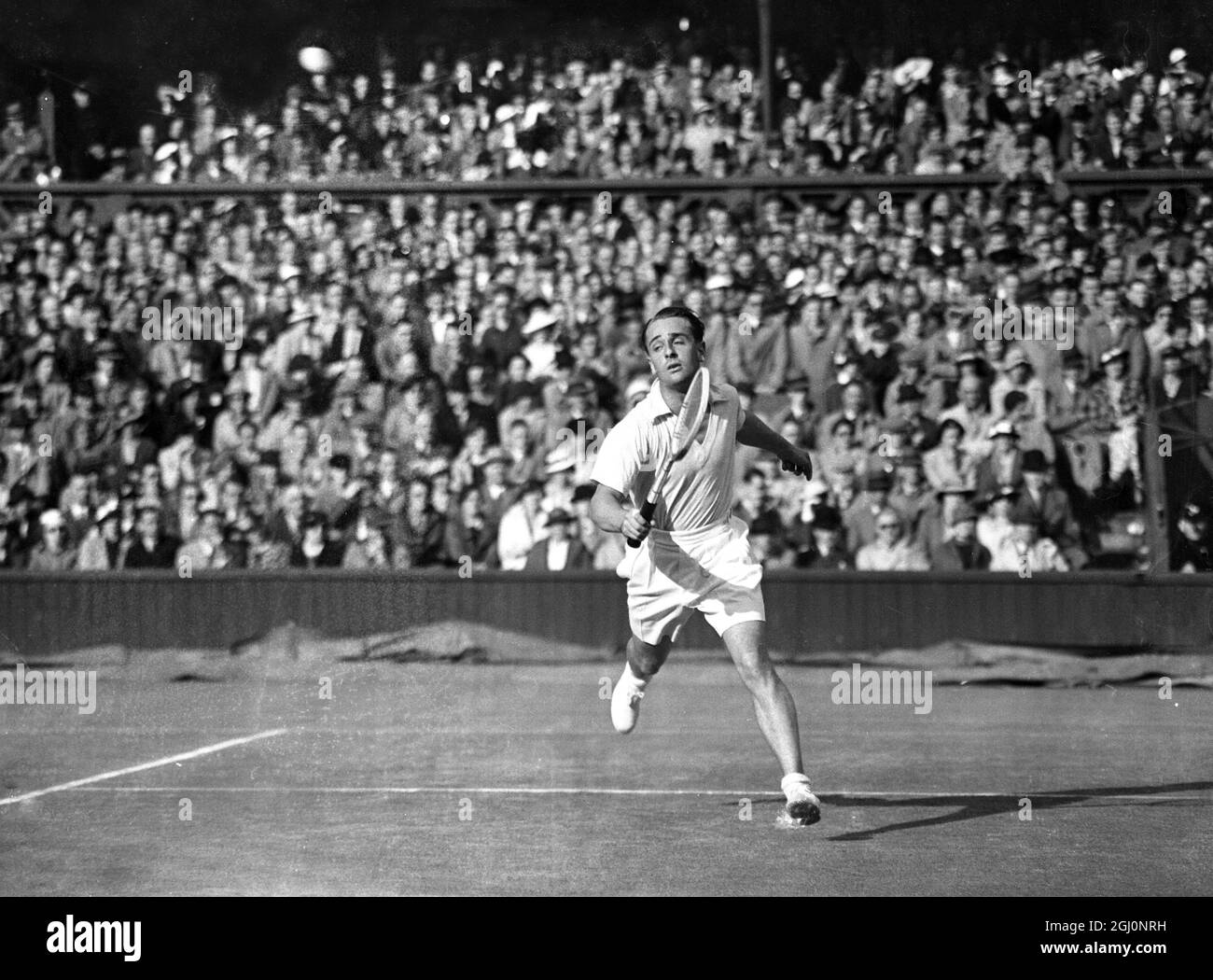 Fred Perry incontrò Adrian Quist in Australia nei singoli del Davis Cup Challenge legato tra Inghilterra e Australia a Wimbledon , Inghilterra . La pioggia ha fermato il gioco più volte . La foto mostra Quist scattando un colpo basso durante la partita . 25 luglio 1936 Foto Stock