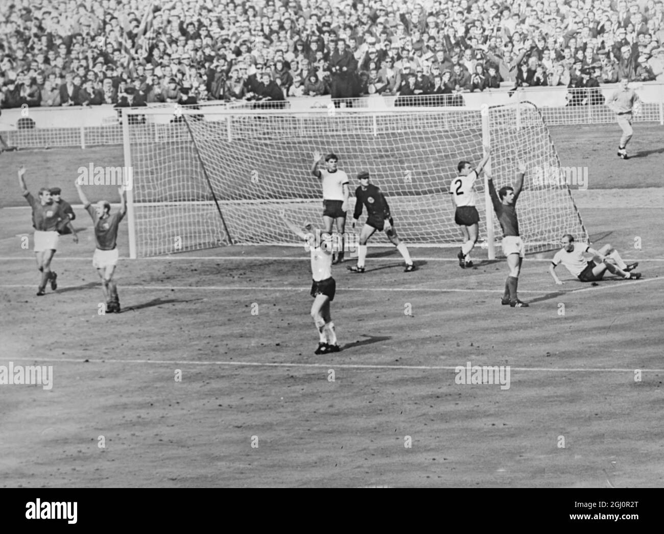 Terzo traguardo contraversiale . Wembely , Inghilterra : Dark - Shirted England Players , Roger H (sinistra ) , Bobby Charlton and Goal Sector , Geoff Hurst (destra ) Appello all'arbitro come i giocatori della Germania occidentale protestano dopo che Hurst aveva segnato l'Inghilterra contraversial terzo gol nella finale della Coppa del mondo 1966 a Wembley ieri . La palla colpì la traversa e rimbalzò verso il basso . Tutti i giocatori inglesi hanno sostenuto che la palla aveva attraversato la linea. L'arbitro ha assegnato il traguardo dopo aver consultato il lineman russo . 30 luglio 1966 Foto Stock