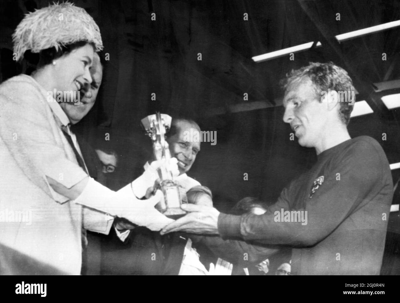 La regina presenta la coppa al Capitano d'Inghilterra. La regina Elisabetta II di Brigiain presenta il Trofeo Jules Rimet World Cup al Capitano d'Inghilterra Bobby Moore, dopo che l'Inghilterra ha sconfitto la Germania occidentale nella finale del torneo World Cup allo stadio Wembley di oggi. L'Inghilterra ha vinto 4-2. 30 luglio 1966 Foto Stock