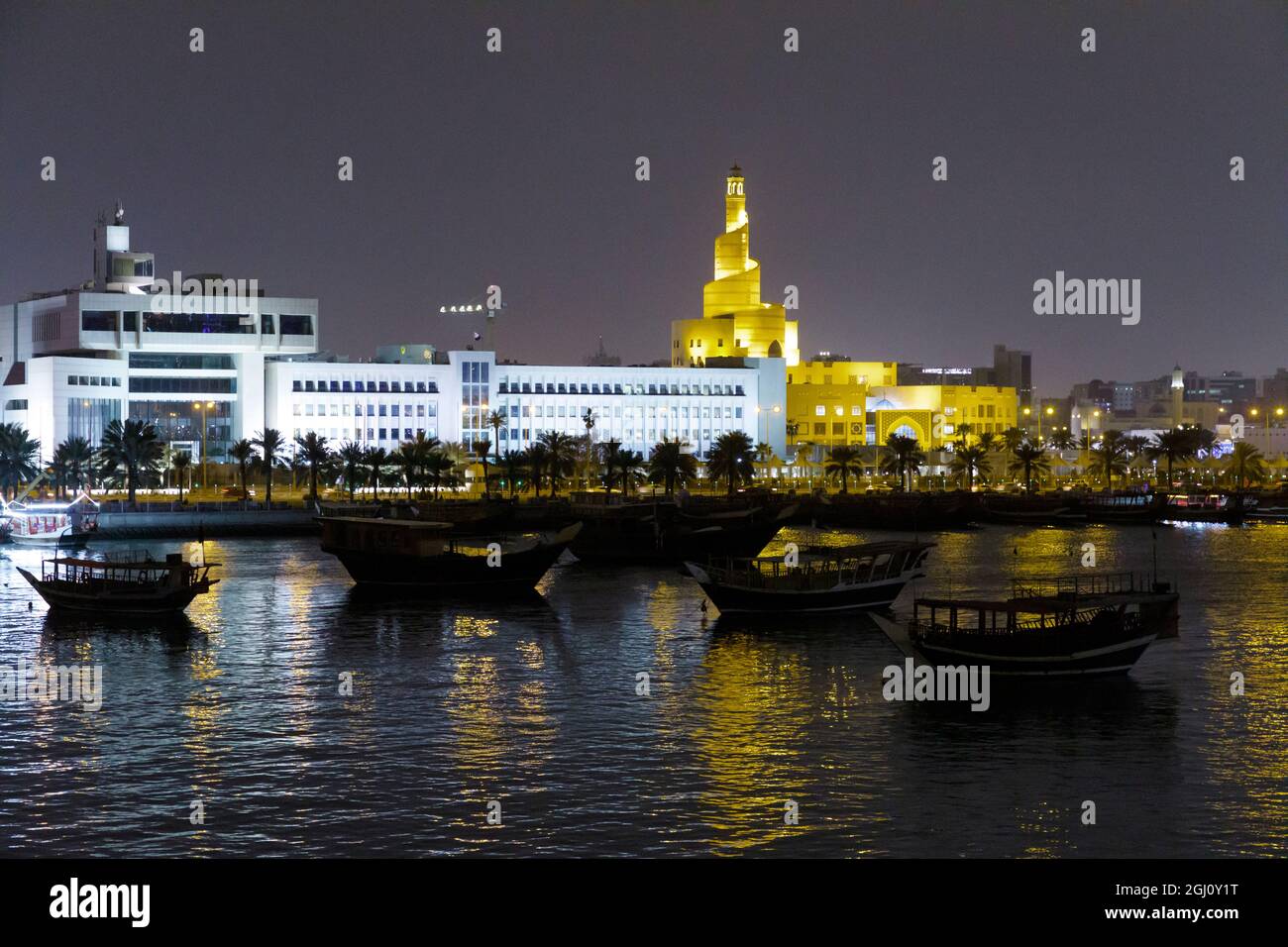 Stato del Qatar, Doha. Dhow porto di notte. A sinistra: Ministero delle Finanze. Destra: Bin Zaid, anche conosciuto come Moschea a spirale o Fanar o cultura islamica del Qatar Foto Stock