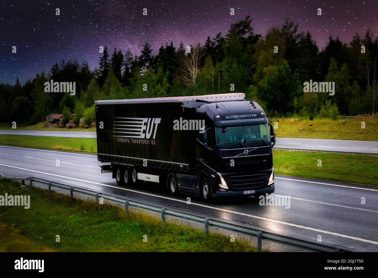 Nuovo semirimorchio Volvo FH nero Euroopa Transpordi OU che trasporta merci in autostrada sotto il cielo stellato di notte. Sostituzione cielo. Finlandia, 2021. Foto Stock