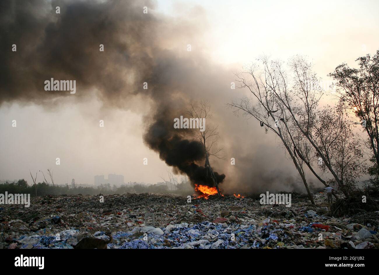 Il fumo denso sorge da un fuoco a terra di spazzatura scarico a Delhi , NCR, India. Foto Stock