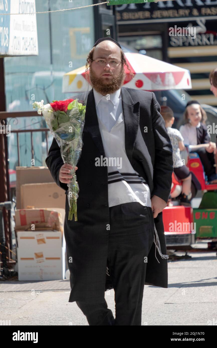 Un uomo ebreo ortodosso acquista fiori per la sua famiglia il giorno prima di Capodanno ebraico. A Williamsburg, Brooklyn, New York Foto Stock