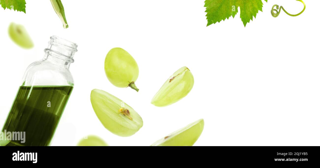 Bottiglia con olio di semi d'uva verde su sfondo bianco. Spazio di copia, disposizione piatta, vista dall'alto. Foto Stock