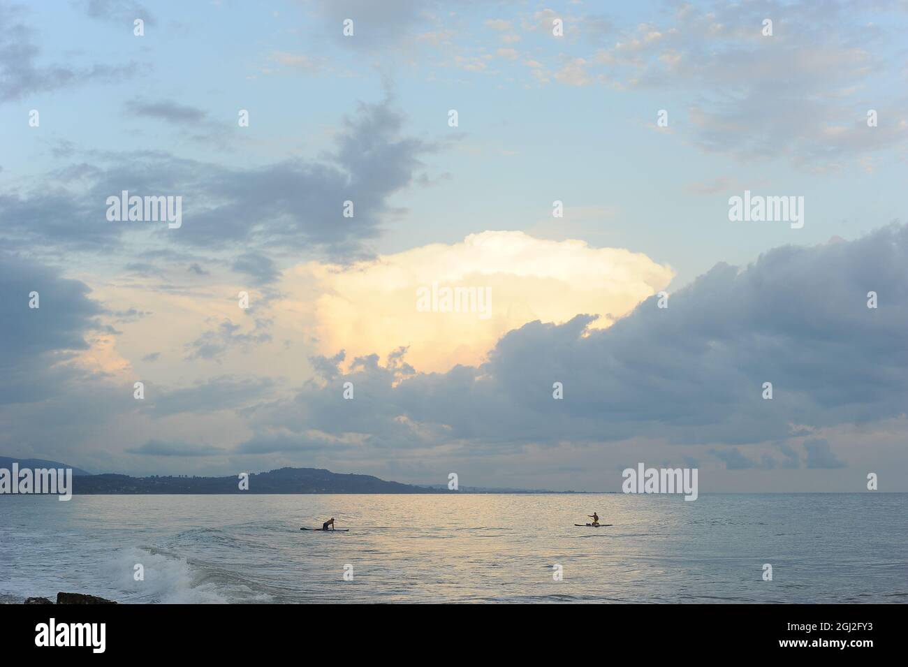 Mar Nero in Abkhazia. Piccole figure di surfisti. Blu pastello tramonto. Riposatevi sul mare. Foto Stock