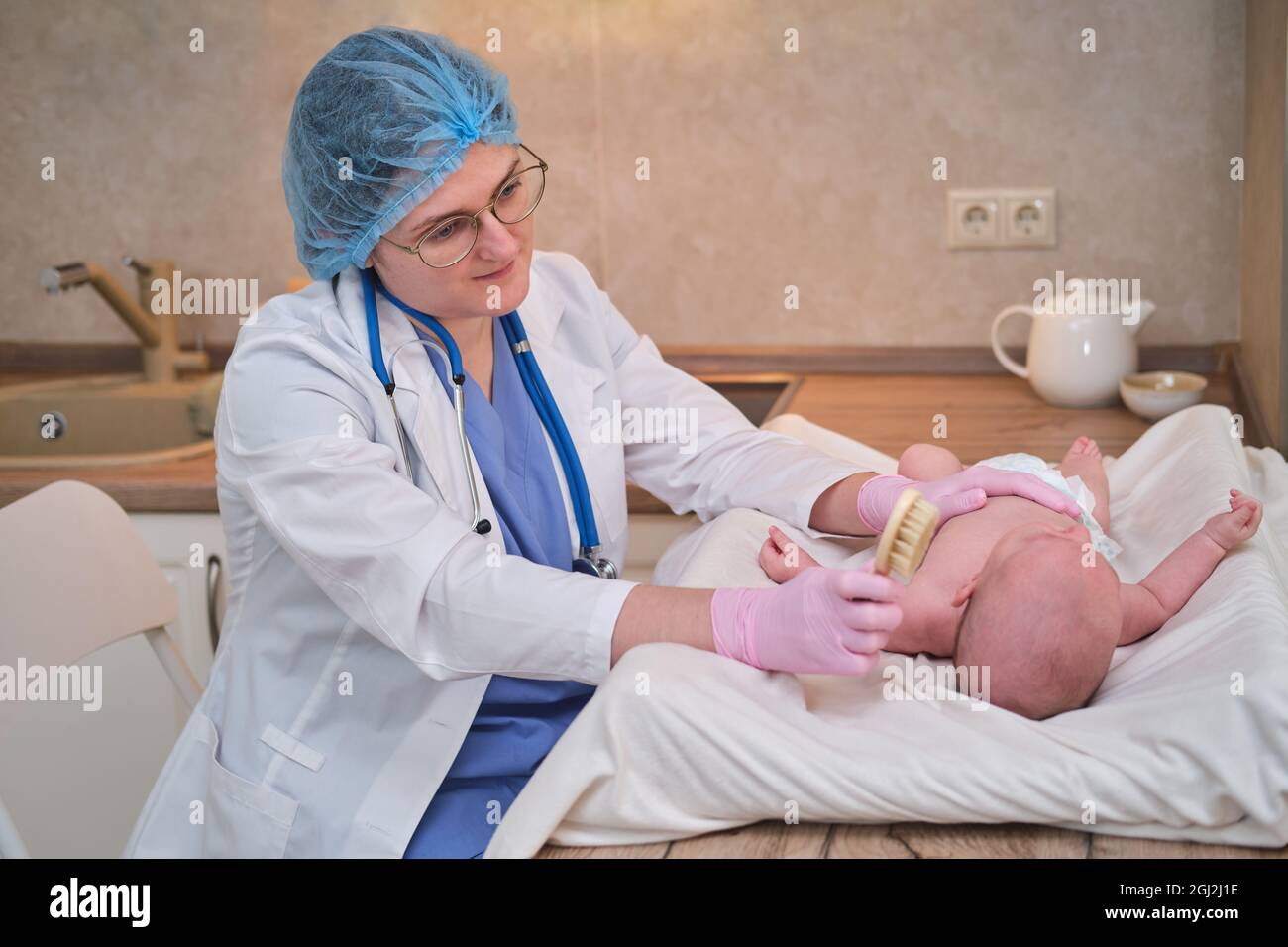 Il medico sta pettinando i capelli di un neonato. Infermiera in uniforme con un pettine in mano per un bambino Foto Stock