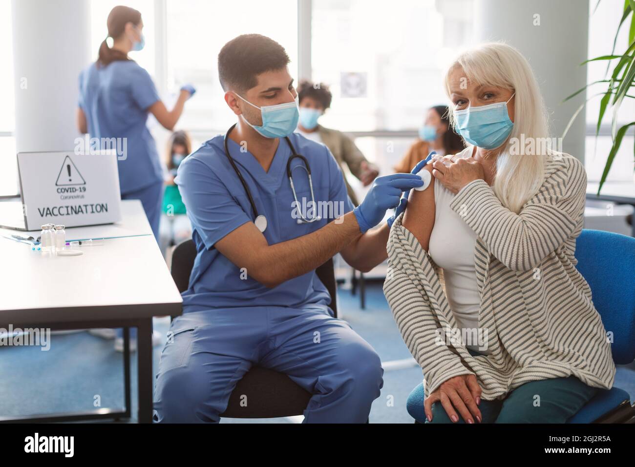 Sperimentazione clinica per il nuovo vaccino moderno Covid-19 durante la pandemia globale. Donna anziana in maschera medica viso che ottiene l'iniezione in ospedale. Preparazione del medico Foto Stock