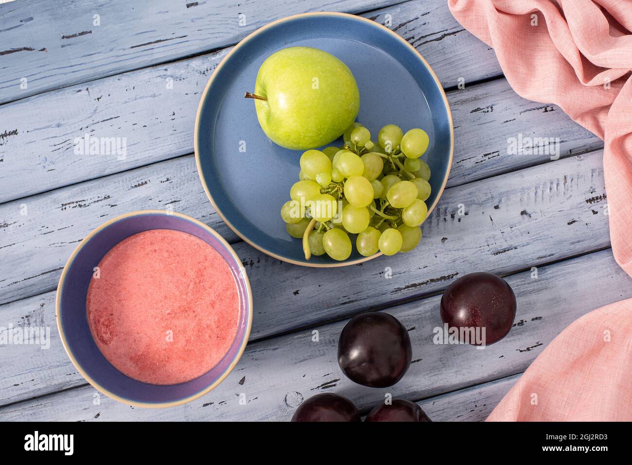 Prugne, uva, mela verde su sfondo di legno blu. Colazione leggera con frutta. Vista dall'alto Foto Stock