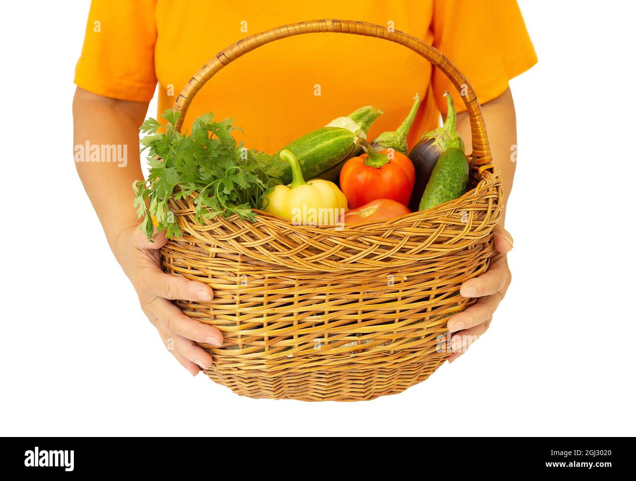 Donna che tiene un cestino di vimini pieno di verdure fresche assortite isolate su bianco Foto Stock