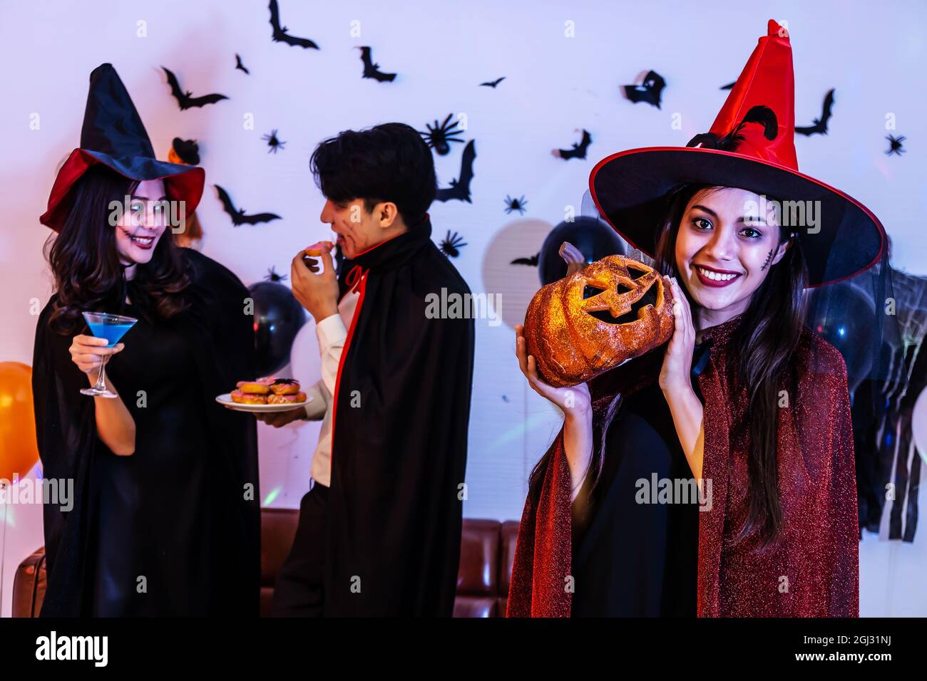 Giovane donna asiatica in costume che celebra Halloween tenendo una zucca scolpita Foto Stock