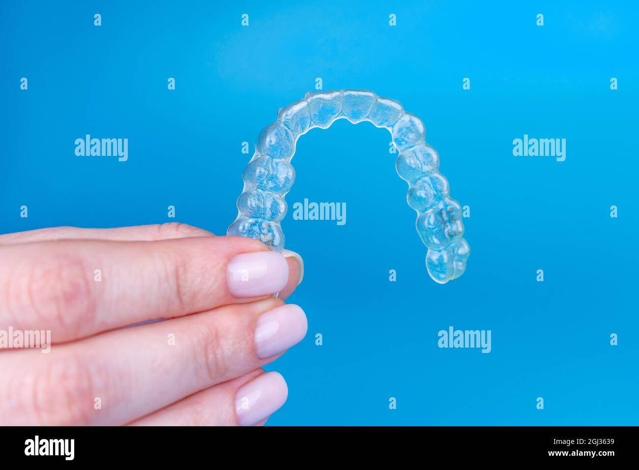 Regge a mano rimovibile invisibile trasparente allineatore invisibile invisalign o in plastica reggiseni ortodontici su sfondo blu Foto Stock