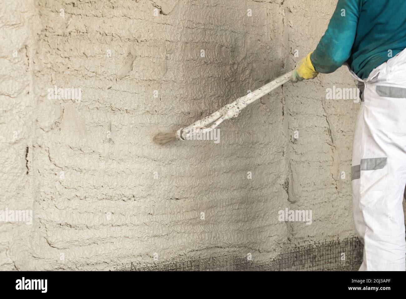 Il processo di applicazione di intonaco a pareti all'interno di un edificio a macchina. Foto Stock