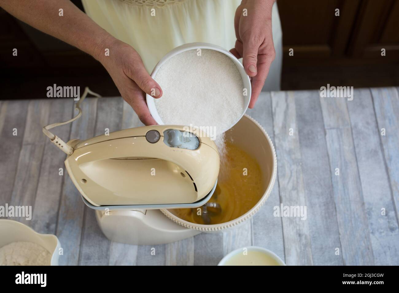 Processo di preparazione della torta. Le mani delle donne aggiungono zucchero al recipiente del mixer per preparare l'impasto. Ricetta passo per torta al cioccolato. Serie. Concetto di cottura. Foto Stock
