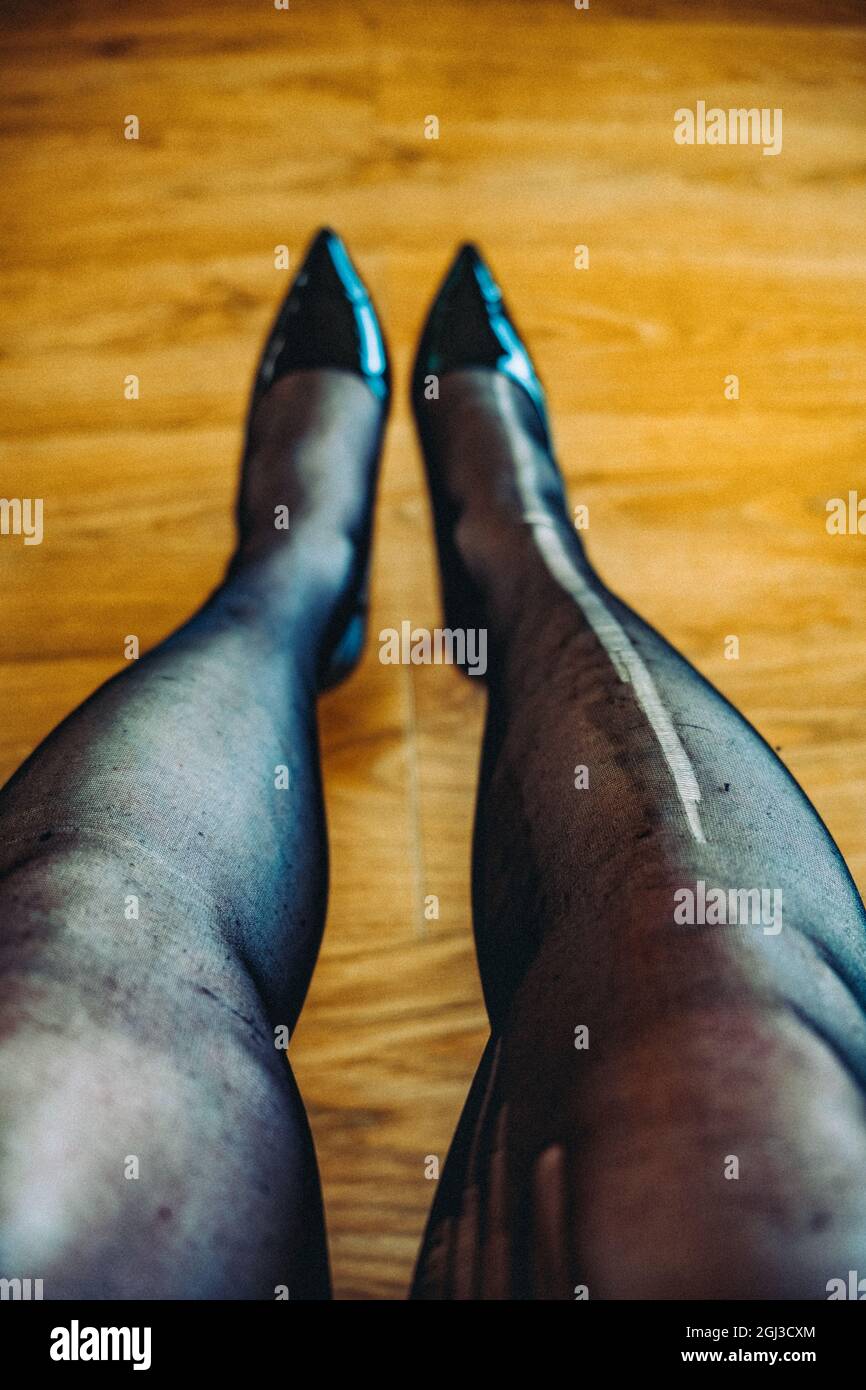 Donna sdraiata su un pavimento di legno con calze strappate Foto Stock
