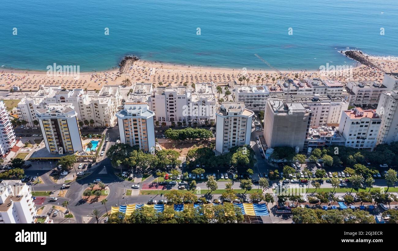 Splendidi paesaggi urbani aerei della città turistica portoghese di Quarteira. Sulla riva del mare durante la stagione balneare con i turisti che stanno prendendo il sole. Foto Stock