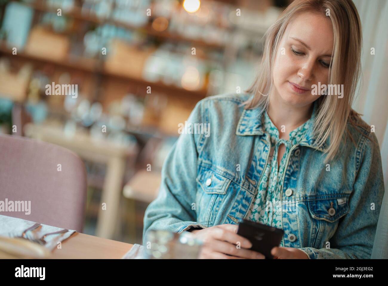 Donna con smartphone è in attesa di una data in ristorante. Foto Stock
