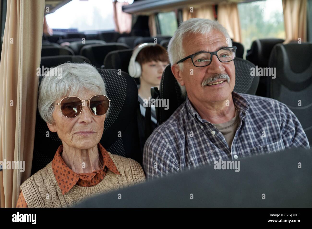 Soddisfare senior caucasica coppia con capelli grigi seduta in autobus mentre si viaggia insieme Foto Stock