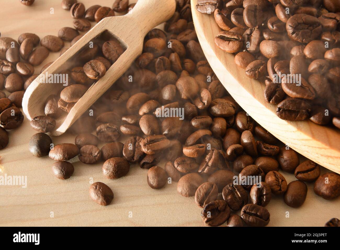 Mucchio di chicchi di caffè naturale selezionati macro su tavola in legno e pala da cucina in legno. Vista dall'alto. Composizione orizzontale. Foto Stock