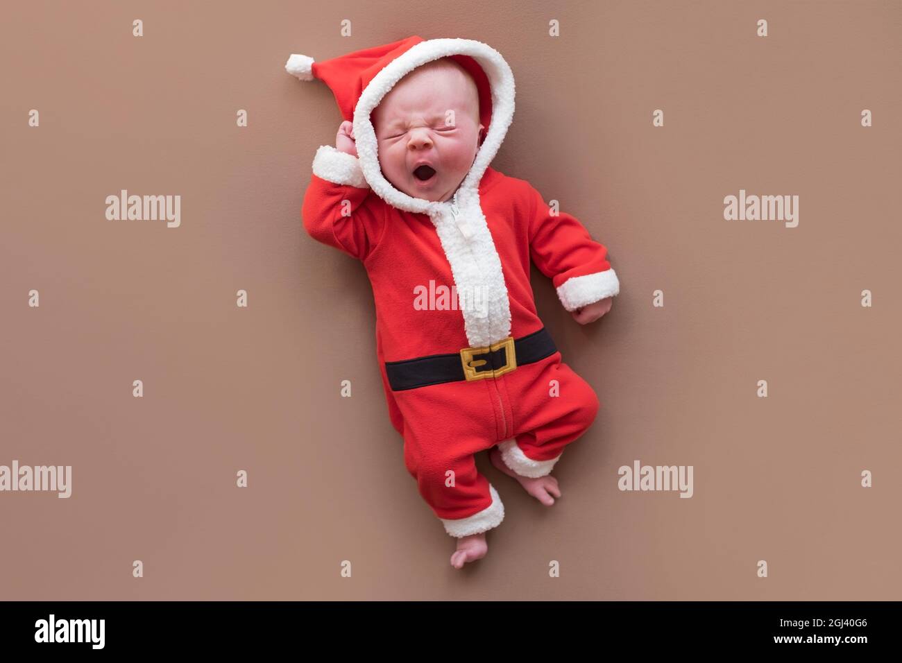 Ragazza neonato vestita in costume babbo natale sbadigliata stanca. Foto Stock