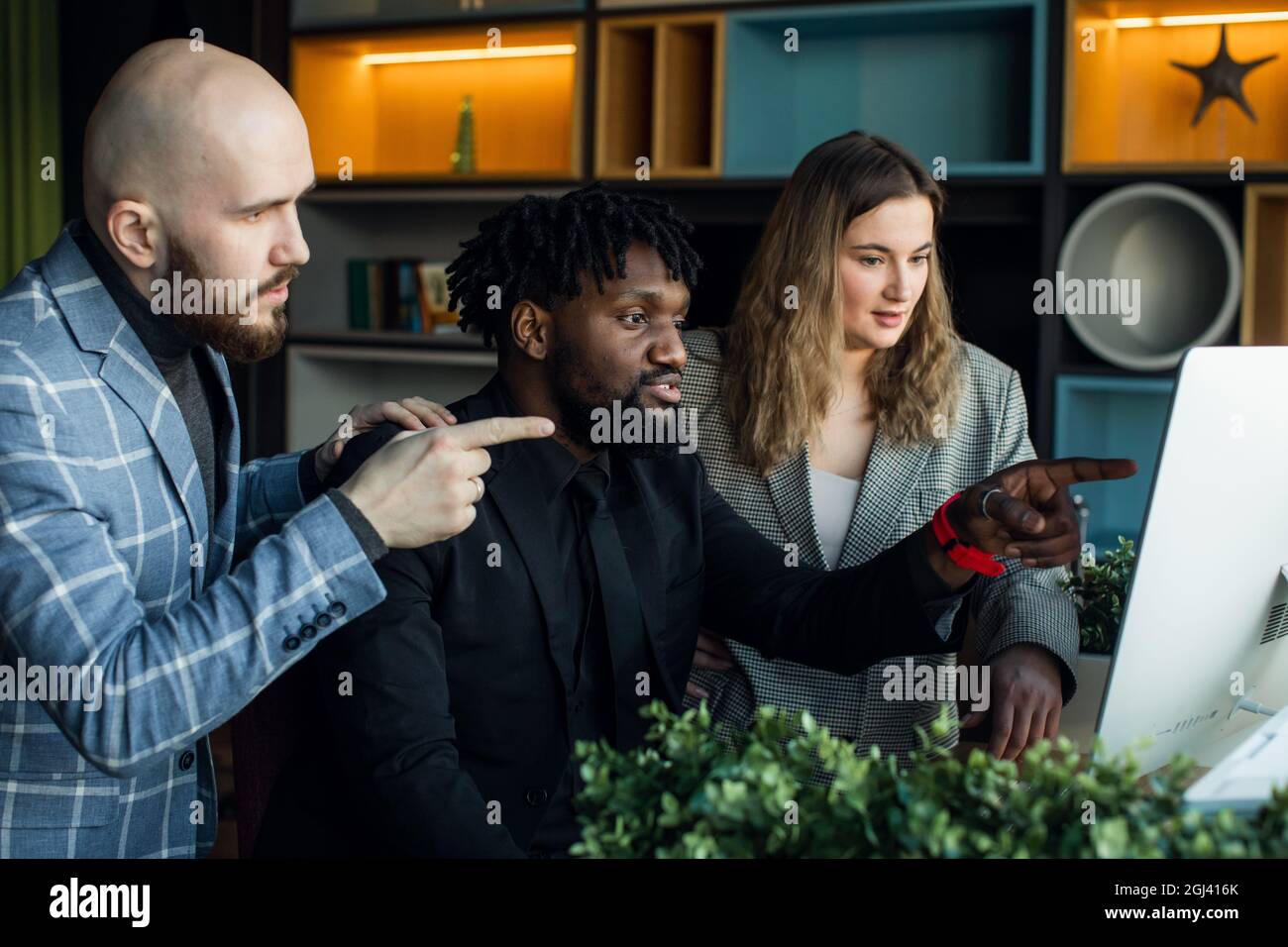 Valutazione completa sul lavoro. Gruppo di giovani uomini d'affari che lavorano e comunicano seduti in ufficio insieme ai colleghi Foto Stock
