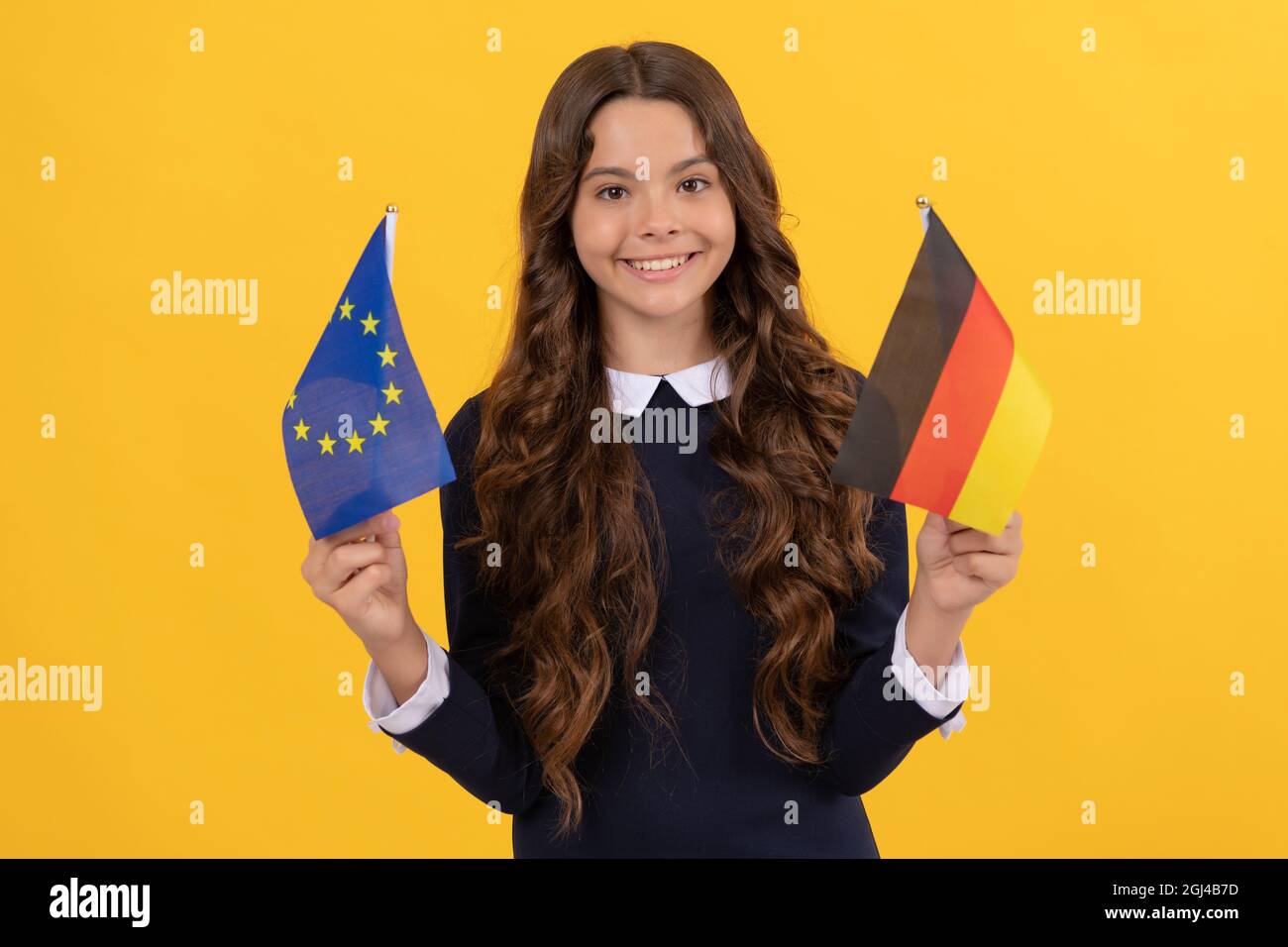 felice capretto tenere unione europea e bandiera tedesca sfondo giallo, germania Foto Stock