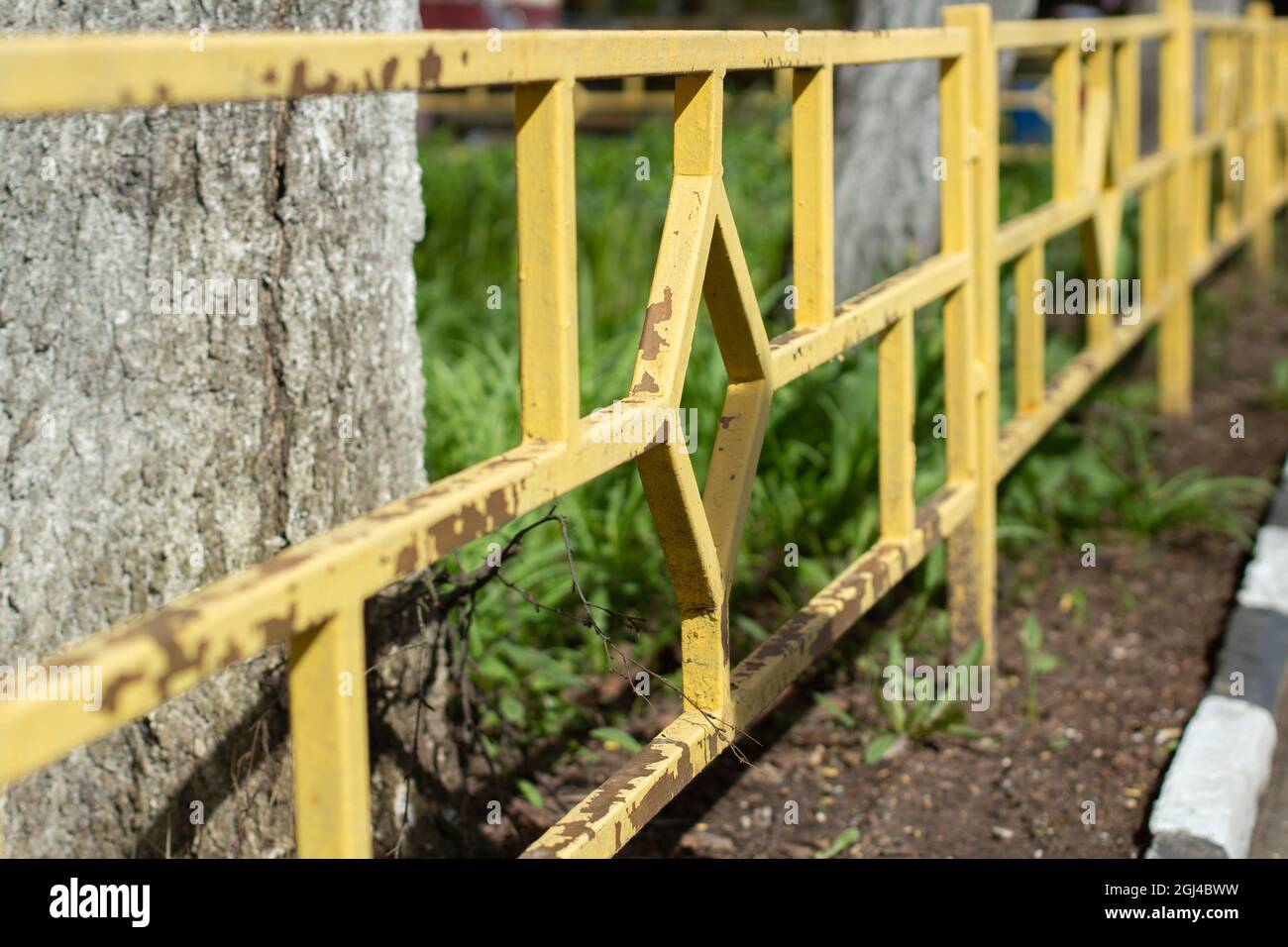 Recinzione gialla con vernice volante. Recinzione aiuole e cortile con una recinzione bassa. Foto Stock