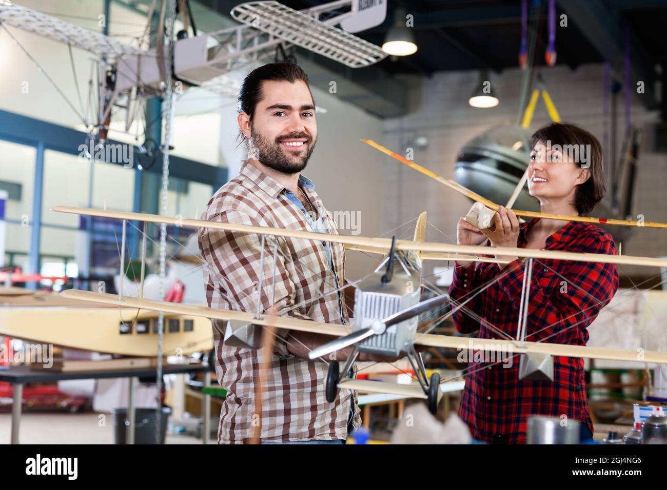 Allegro team di appassionati di aerei che hanno modelli di aeroplani sportivi in officina Foto Stock