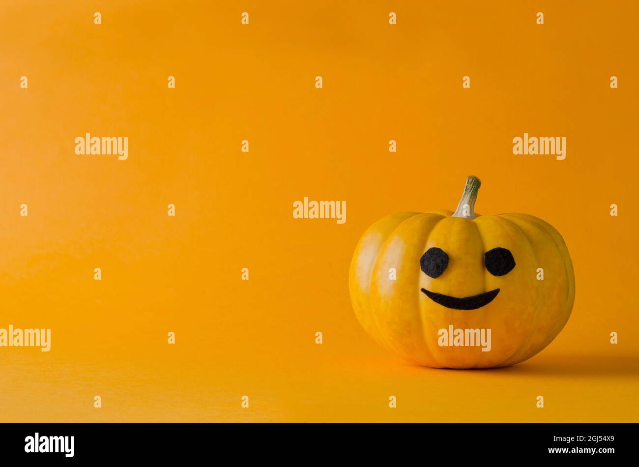 Ciao autunno. Sfondo minimalista di Halloween. Divertente zucca arancione su sfondo arancione, monocromatica, spazio di copia Foto Stock