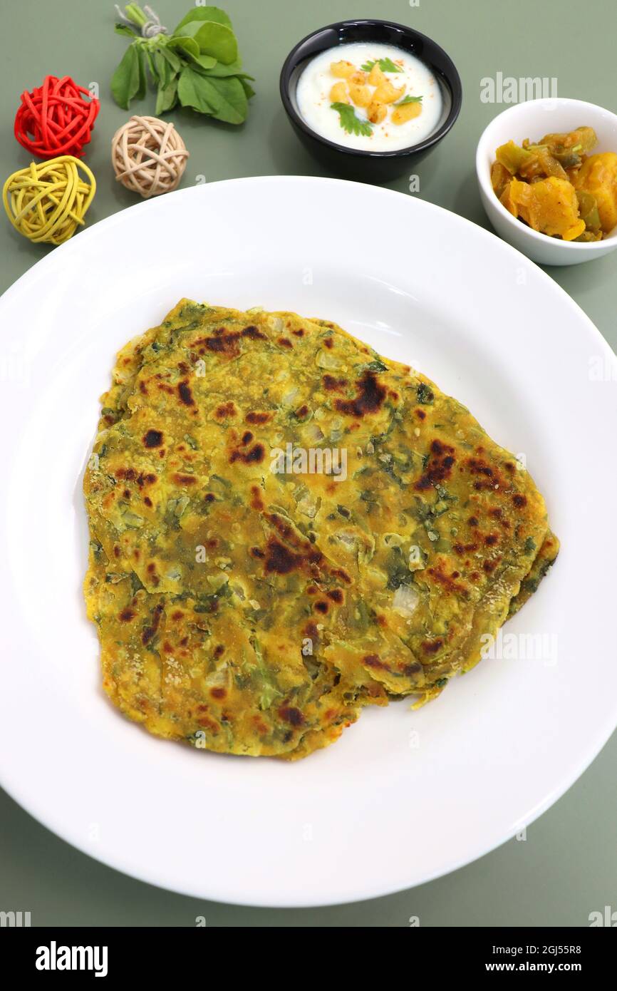 Un cibo chiamato Methi paratha o Methi thepla è un piatto indiano per la colazione servito con curd boondi raita e capsicum sabzi. Masala Fenugreek roti. Foto Stock