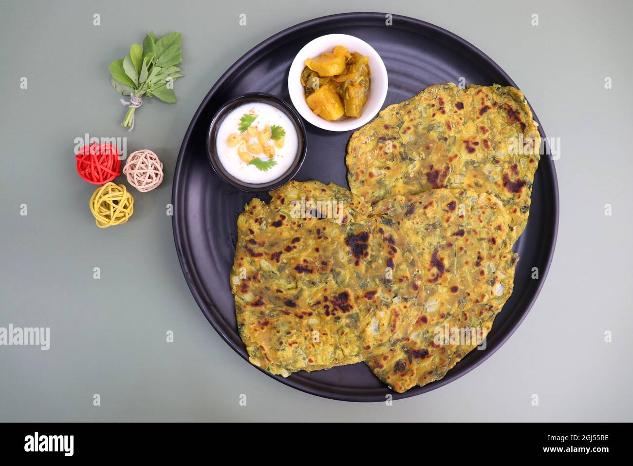 Un cibo chiamato Methi paratha o Methi thepla è un piatto indiano per la colazione servito con curd boondi raita e capsicum sabzi. Masala Fenugreek roti. Foto Stock