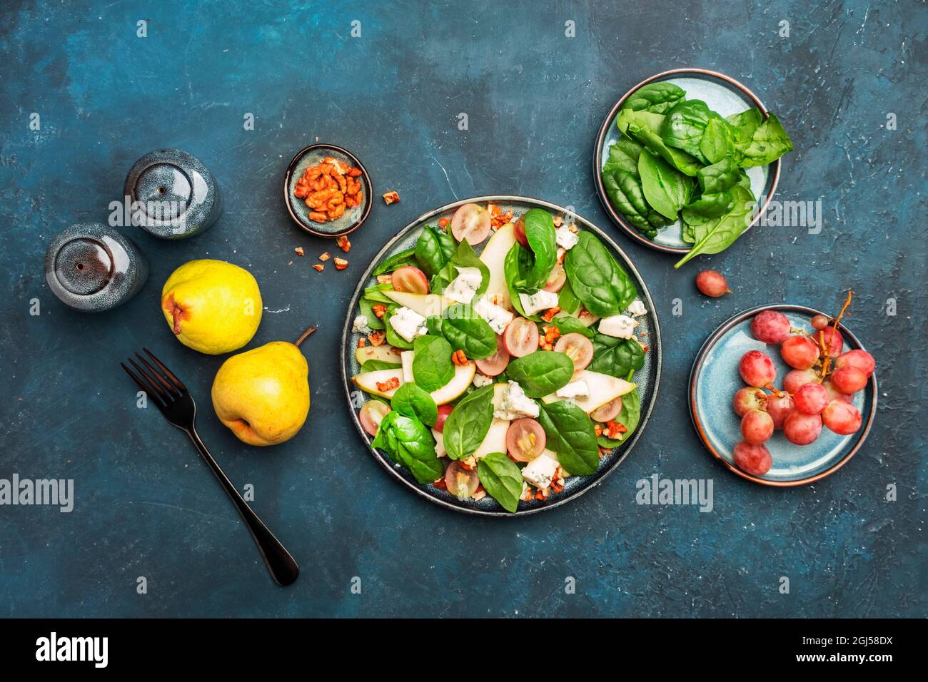 Insalata con pera, formaggio blu, spinaci, uva, noci su sfondo blu, vista dall'alto, spazio copia Foto Stock
