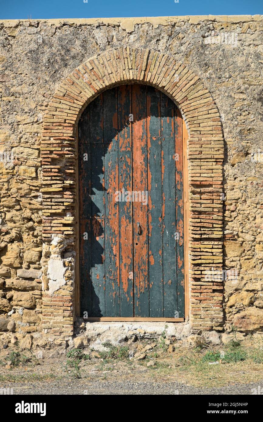Ingresso ad arco in mattoni rossi con vecchia porta verde dipinta di architettura rurale siciliana Foto Stock