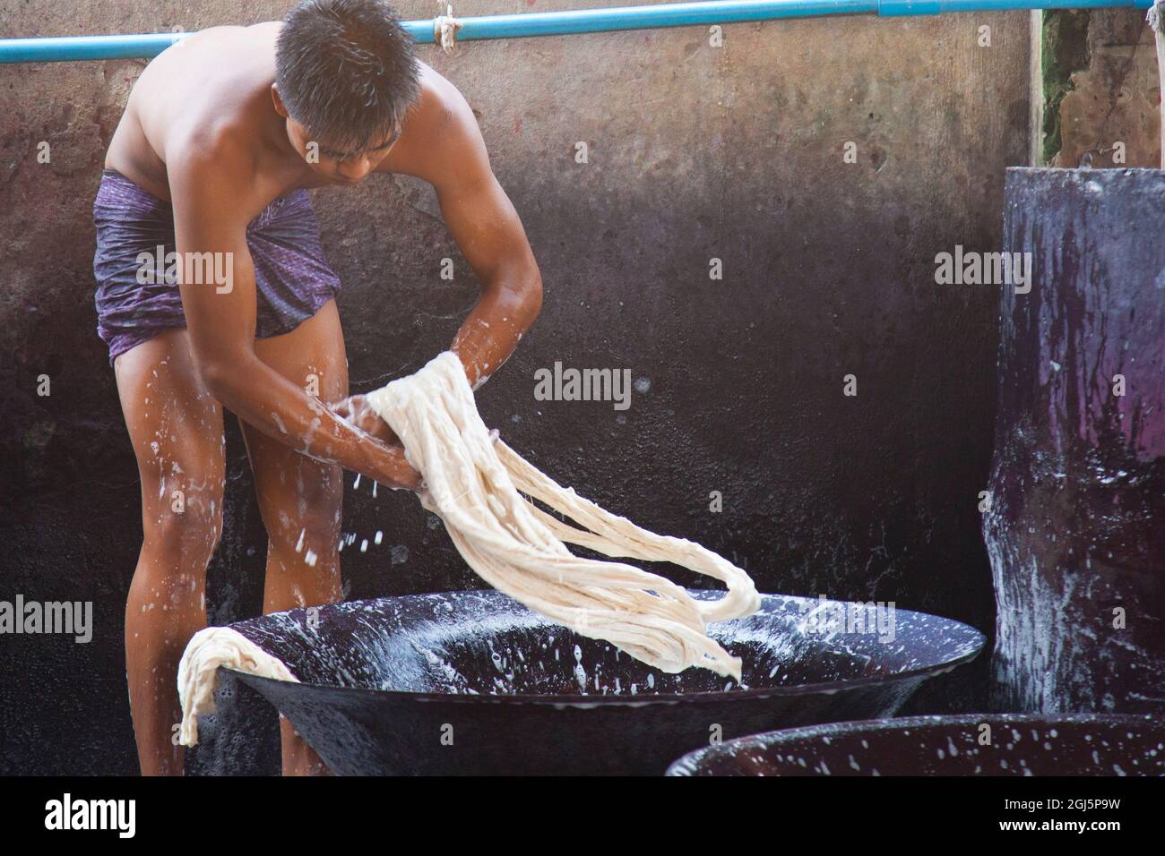 Gli uomini che lavorano e schiappano nei bidoni di lavaggio in fabbrica di tessuti a Mandalay, Myanmar. Foto Stock