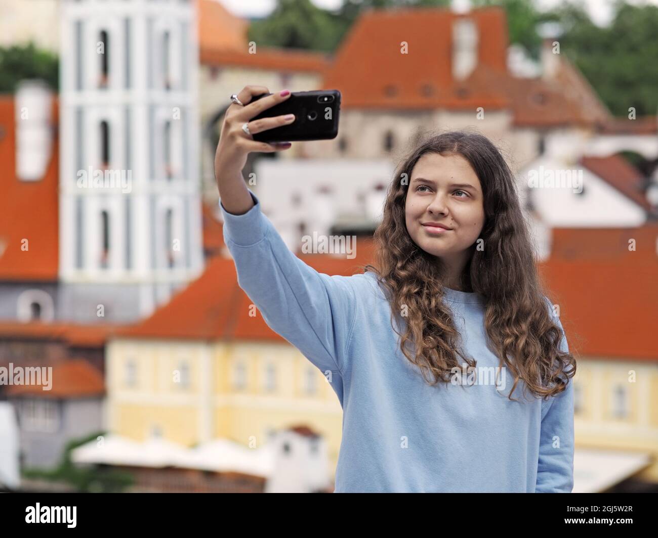Giovane ragazza scatta una foto selfie sullo sfondo della città storica, la città ceca Krumlov, repubblica Ceca Foto Stock