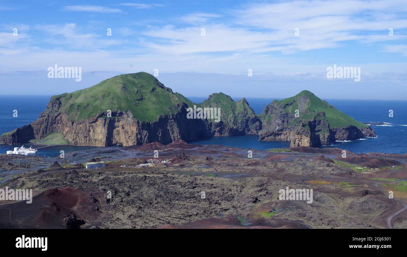 Bella vista su Heimaey, Islanda, presa dal vulcano Eldfell. Flusso di lava marrone in primo piano. Mare blu e cielo con nuvole bianche nel backgroun Foto Stock