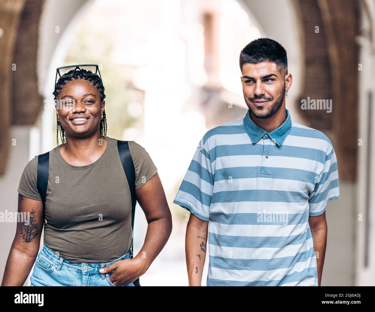 Due giovani di diversa etnia sorridono mentre camminano per una città Foto Stock