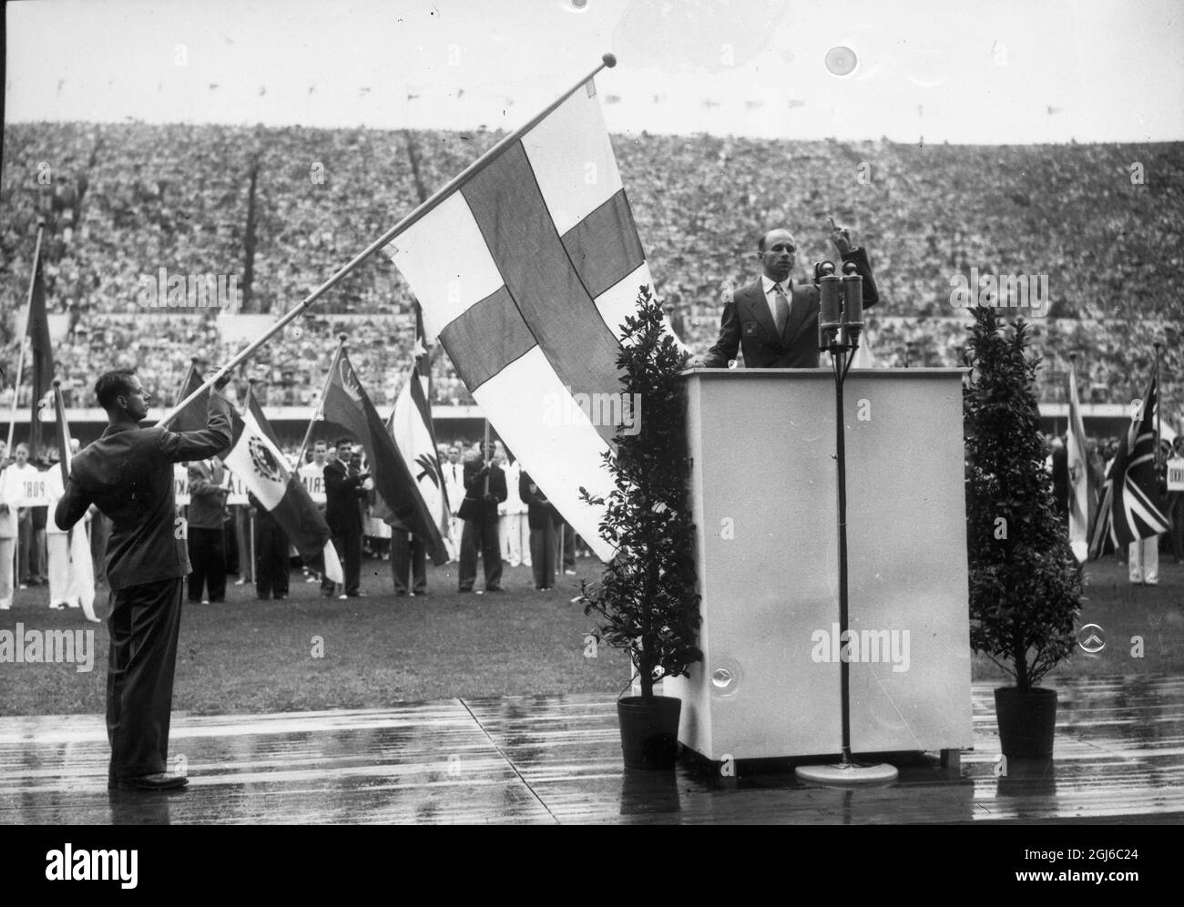 GIURAMENTO OLIMPICO - CERIMONIA DI PREMIAZIONE - LA RUSSIA NON riesce a far vacolare la LORO BANDIERA Helsinki : l'atleta finlandese, Neikki Savolainen , che presta giuramento accanto alla bandiera finlandese , durante la cerimonia di apertura dei Giochi Olimpici del 1952 qui. Nota la bandiera russa non è immersa ( vista a destra ) . 19 luglio 1952 Foto Stock