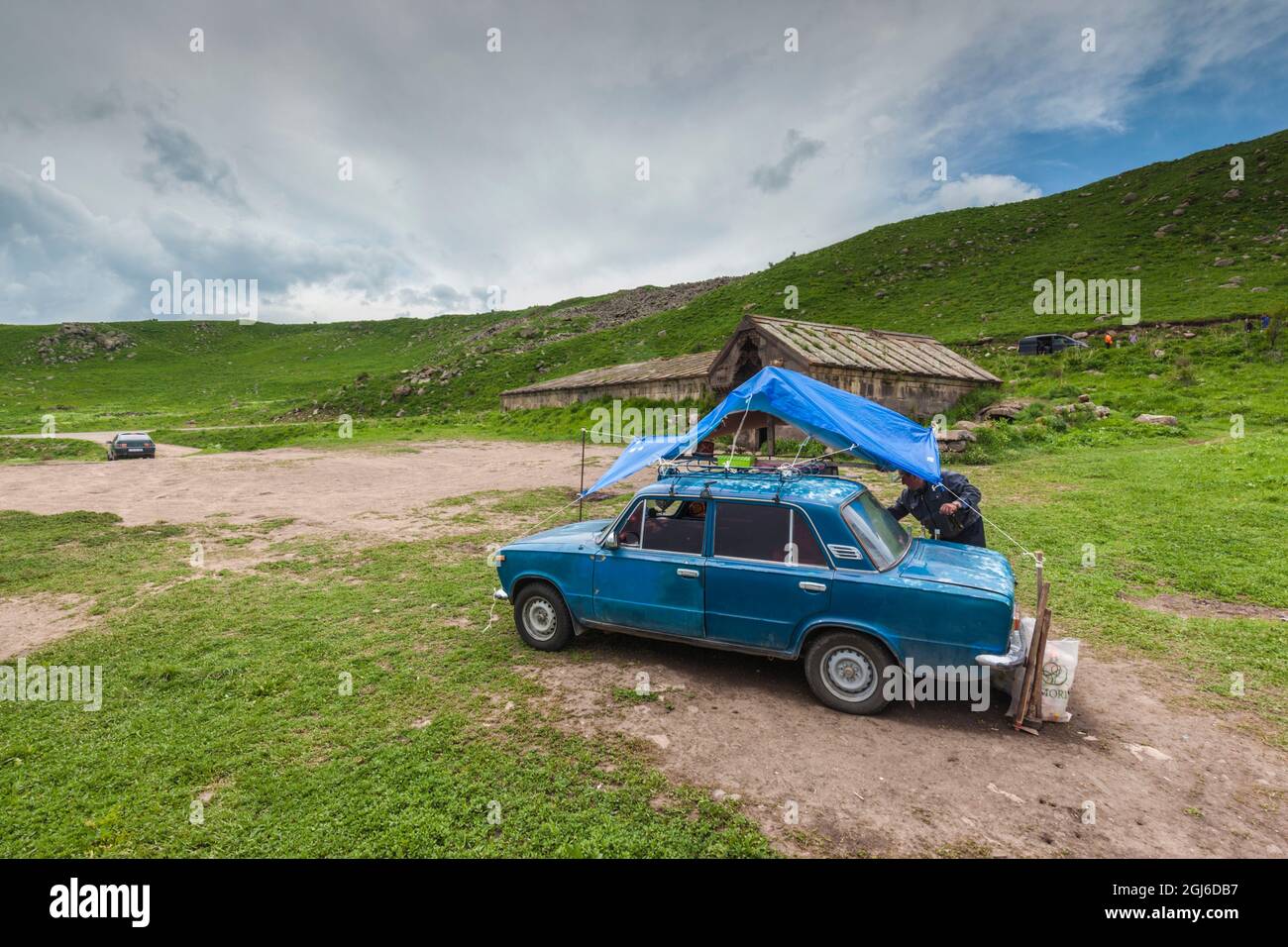 Armenia, Selim. Passo Selim, Selim Caravanserai, 14 ° secolo, sosta di riposo in cima alla montagna vecchia per il commercio di roulotte, custode con l'auto di Zhiguli di epoca sovietica. Foto Stock