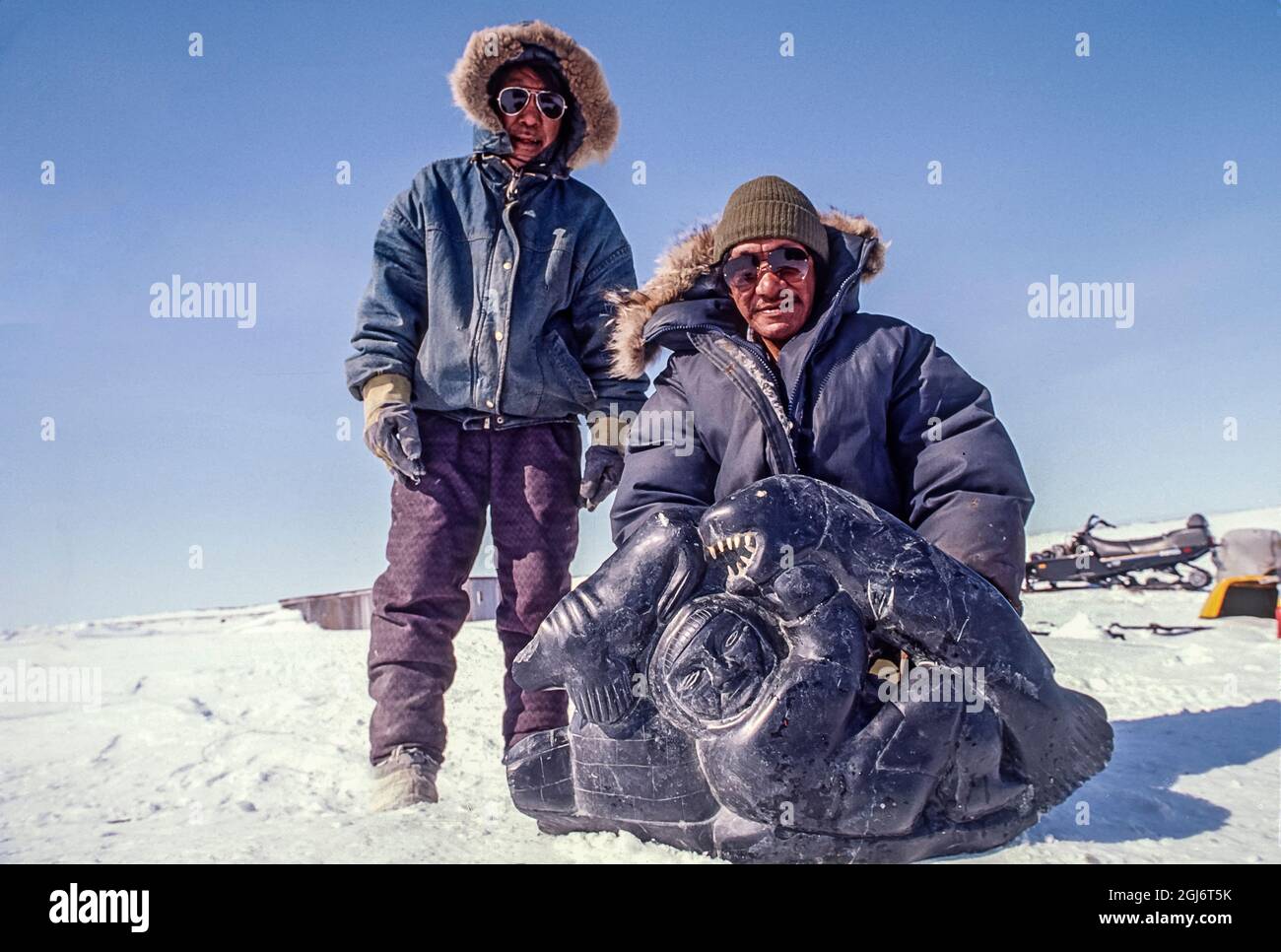 Lago Baker, Nunavut, Canada. Gli anziani inuit vestiti con abbigliamento moderno mostrano una delle loro sculture in pietra. (Solo per uso editoriale) Foto Stock