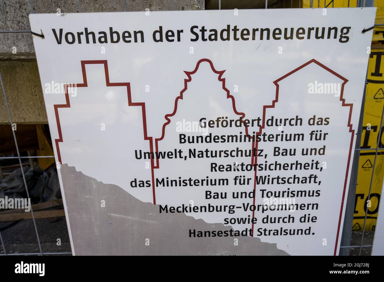 08 settembre 2021, Meclemburgo-Pomerania occidentale, Stralsund: Un cartello da costruzione con la scritta "progetto di rinnovamento urbano" è appeso su una recinzione. La città anseatica di Stralsund, menzionata per la prima volta nel 1234, è uno dei magneti turistici nel Meclemburgo-Pomerania occidentale a causa dei suoi oltre 500 edifici elencati, la maggior parte dei quali sono stati ampiamente restaurati negli ultimi anni con l'aiuto dell'agenzia di ristrutturazione fiduciaria Stadterneuerungsgesellschaft Stralsund mbH (SES). Il centro storico medievale di Stralsund, insieme alla città anseatica di Wismar, è stato incluso nel mondo dell'UNESCO Foto Stock