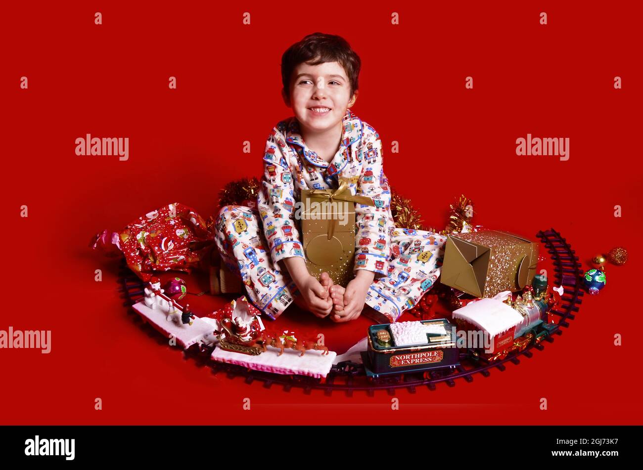 Giovane ragazzo felice in pigiama con un sacco di regali di Natale Foto Stock