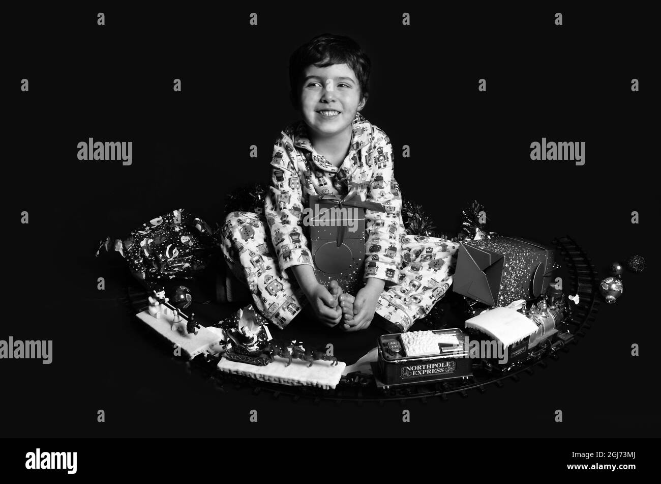 Giovane ragazzo felice in pigiama con un sacco di regali di Natale Foto Stock