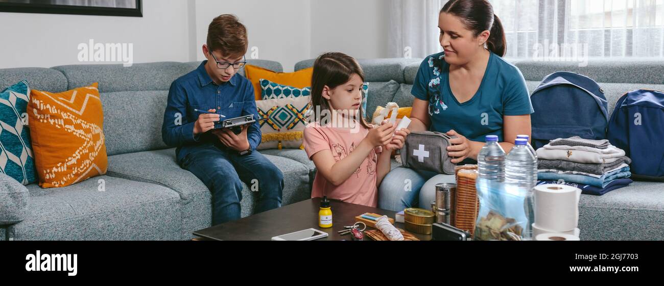 Madre che prepara lo zaino di emergenza con i suoi figli Foto Stock