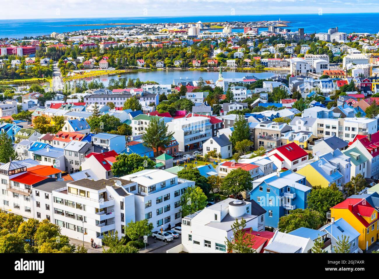 Piccolo lago di Tjornin blu Oceano Mare colorato blu rosso bianco verde Case strade, Reykjavik, Islanda. Foto Stock
