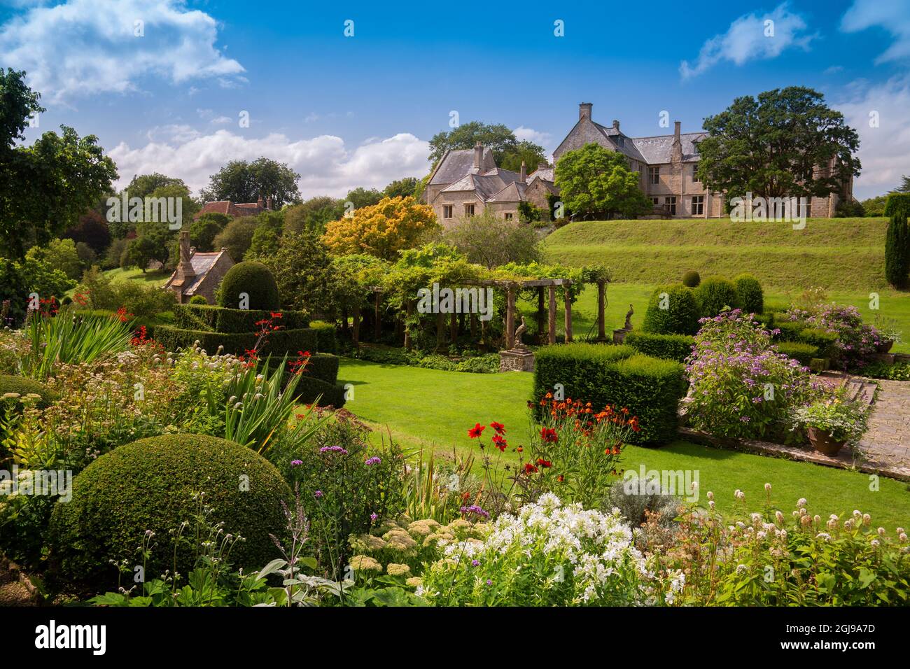 I confini colorati e topiary nel giardino italianate Fountain Court a Mapperton House, Dorset, Inghilterra, Regno Unito Foto Stock